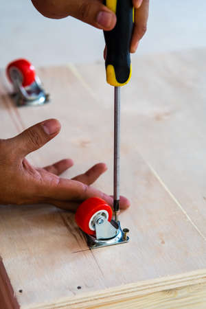 Fixing castor wheel to the wooden plywood, furniture making.の写真素材