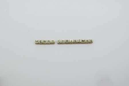 merry christmas spelled out in gold dice blocks on white background.