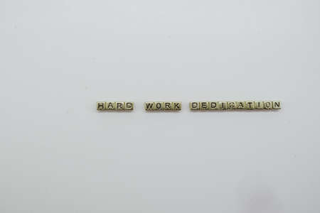 Hard Work Dream Big spelled out in gold dice blocks on white background.