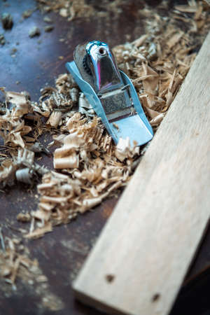 Wood shavings carpenter working with a metal spokeshave and a blurry background. Light beige colored...