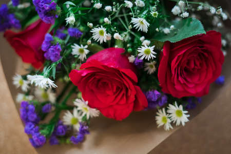 bouquet of roses arrangements of flowers in a paper wrapper on wooden backgroundの写真素材