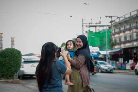 Muslim mother and toddler taking photo at the street in Thailand.の写真素材