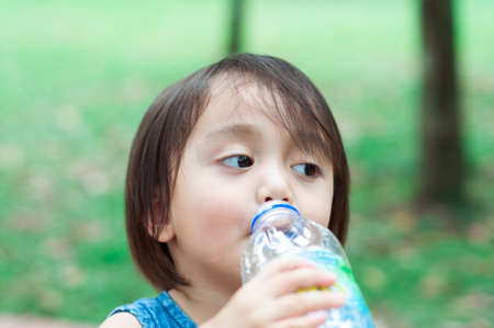 Asian toddler girl drinking water from the plastic water bottle.の写真素材