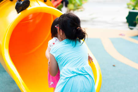 Kids at the outdoor playground. Children play in sunny park. Activity and amusement center in kindergarten or school yard. Child on colorful slide. Toddler kid outdoors.の写真素材