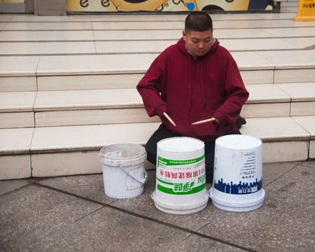 WUHAN,CHINA - April 4, 2019 - A man is playing drum from recycled paint pail on the street.のeditorial素材