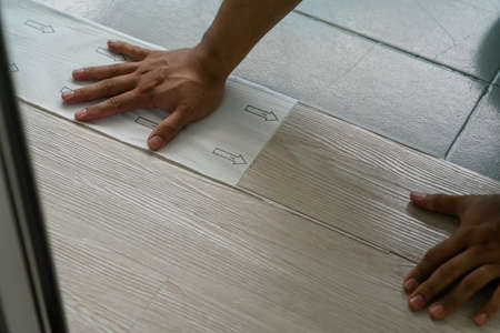 A person installing new vinyl tile floor, a DIY home project.の写真素材