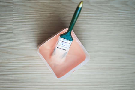 Copy space with a paint brush in a box full of paint on wooden clean floor. Top viewの写真素材