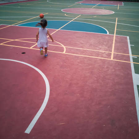 Asian Toddler playing basketball at the basketball court in the evening.の写真素材