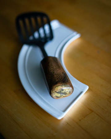 Metal slicer with handmade wooden handle on a white plate and wooden backgroundの写真素材