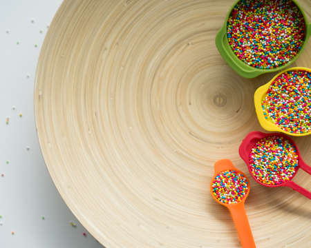 Colourful Sugar sprinkles in measuring cups. Decoration for cake and ice-cream and cookies. Top view, Flat lay on wooden background.の写真素材