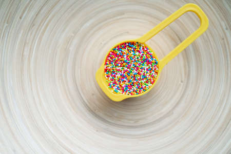 Colourful Sugar sprinkles in measuring cups. Decoration for cake and ice-cream and cookies. Top view, Flat lay on wooden background.の写真素材
