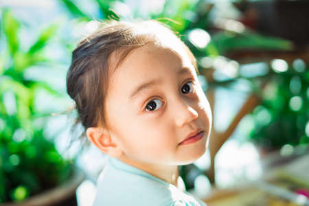Outdoor portrait of an Asian little kid  under the sunlight on her face.の写真素材