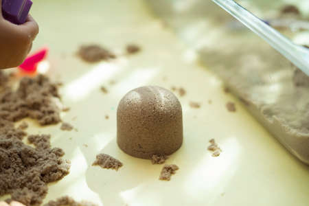 Child's hand playing with kinetic sand in preschool. The development of fine motor concept. Creativity Game concept.の写真素材