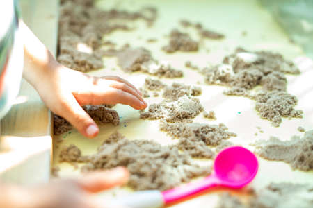 Child's hand playing with kinetic sand in preschool. The development of fine motor concept....