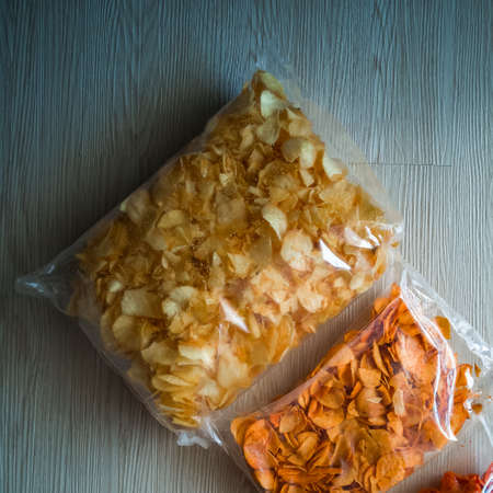Variety Salty Kerepek Chips Food in a plastic packaging container on a wooden floor.