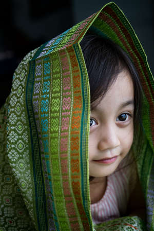 Portrait of cute Asian toddler, kid, girl during Hair Raya, Eid Mubarak celebration in Malaysia. Wearing traditional songket shawl.の写真素材