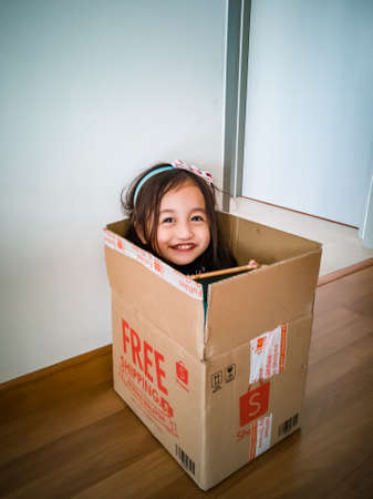 Kuala Lumpur, Malaysia - March 16, 2020: Happy child playing in Shoppee cardboard box. Kid having fun at home. Free Shipping text on the box.のeditorial素材