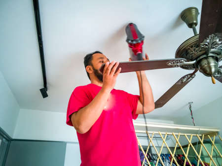 Cleaning the ceiling fan using vacuum cleaner.の写真素材
