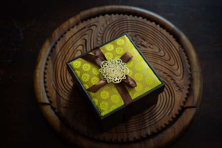 Yellow gift boxes with golden brooch. Traditional songket on one of the boxes. Unique luxury gifting.の写真素材