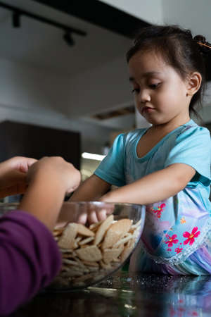 Kids making Kek Batik or Malaysian Triple Chocolate Dessert. Doing the initial steps, crushing the cookies into tiny pieces.の写真素材