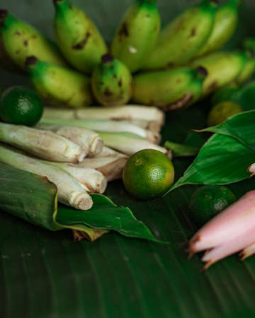 Asian food ingredient with calamansi, lemongrass, tumeric leaves and bananas on a banana leaf background.の写真素材