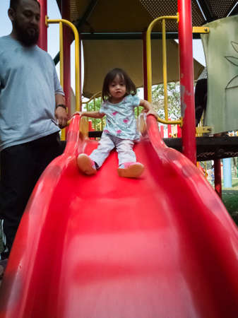 Toddler at the slide playground. Fatherhood love concept.の写真素材