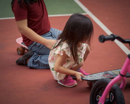 Toddler girl moving a penny board, skateboard at the basketball court. motion shot.の写真素材