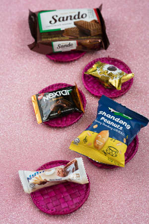 Kuala Lumpur, Malaysia - Jun 27, 2020: Individually packaged Malaysian food products on a pink background.のeditorial素材