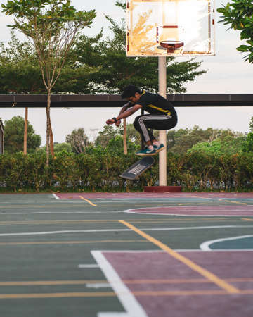 Kuala Lumpur, Malaysia - July 1, 2020: Greenery trees near the basketball court with skateboarder in motion.のeditorial素材