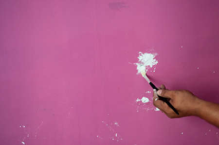 Filling holes with white filler on the wall before painting process.
