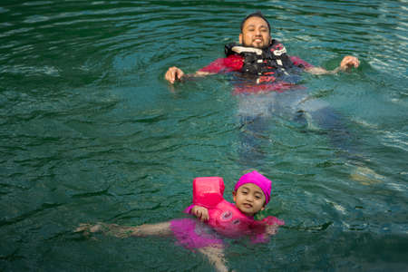 Asian family swimming at the Kenyir Lake, Malaysia.