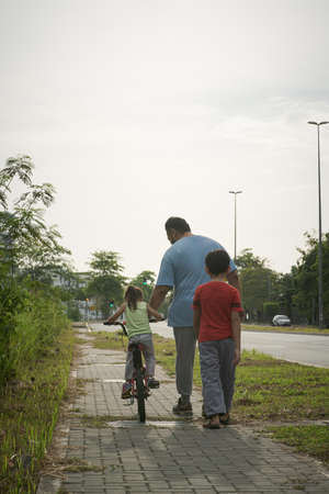 Asian family walking with bicycle. Outdoor togetherness.の写真素材