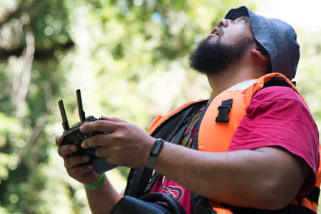 Operating drone flying or hovering by remote control by a man in outdoor.