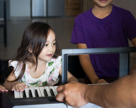 Asian children young kids playing keyboard piano at home.の写真素材