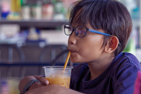 Malay asian child drinking at a hawker local style restaurant.の写真素材