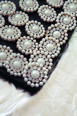 round brooch with pearls on a black and silver background.