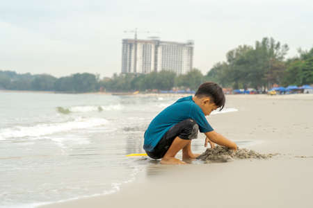 A young boy playing sand at the beach - close up photo of the sand.の写真素材
