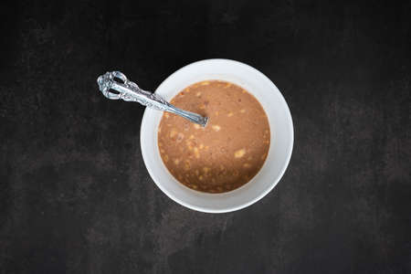 breakfast of healthy banana flakes with chocolate, oat, granola in a white bowl.