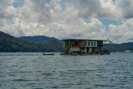 Kenyir, Malaysia - July 23, 2020: Houseboat crusing through the lake with mountain view at Kenyir Lake. Tasik Kenyir is a man made lake.のeditorial素材