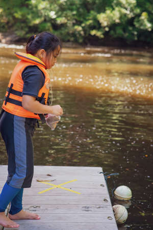 Young girl feeding fish at the Kelah River fish sanctuary.の写真素材