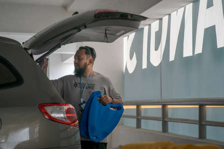 Kuala Lumpur, Malaysia - Sept 26, 2020:  Bearded man packing luggage in a SUV. Joyful man placing...