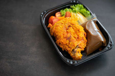 Chicken Chop and fries with  Black Pepper sauce and vegetables. in a take away container.の写真素材