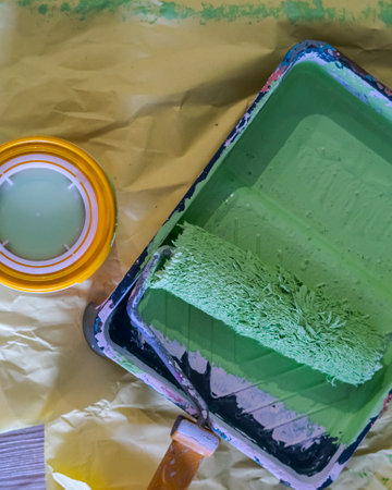 Paint roller in paint tray with green color in the tray on yellow paper.の写真素材