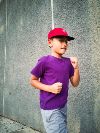Young boy runs at the town concrete park.