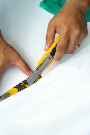 Cutting the White laminated sticker on the furniture. installing sticker at home. Selective focus.の写真素材