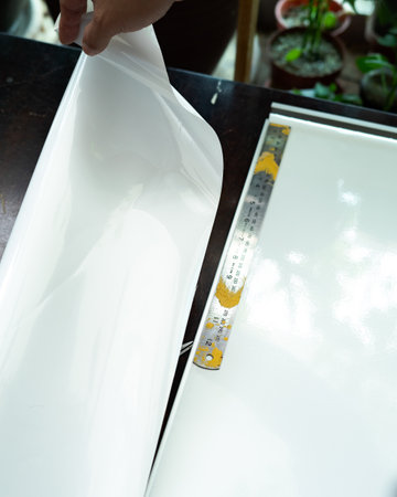 Cutting the White laminated sticker on the furniture. installing sticker at home. Selective focus.