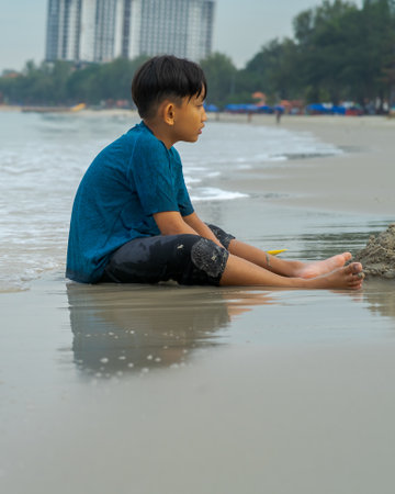 A young boy playing sand at the beach - close up photo of the sand.の写真素材