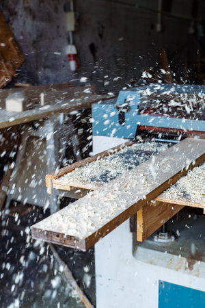 Carpenter working automated sanding machine for wood boards.