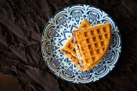 Fresh waffles with peanut butter and chocolate spread on a decorated plate.