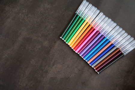 Colorful markers on a dark background. Concept of education, learning, creative and arts and crafts.